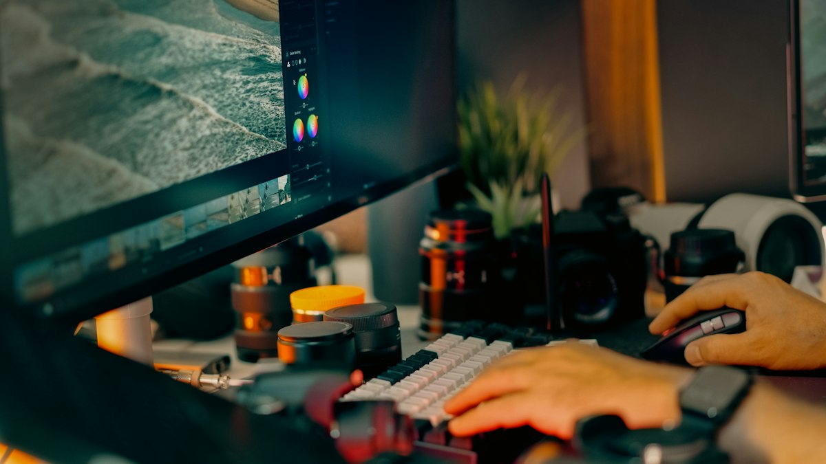 Detalhe de mãos no teclado em uma estação de edição com fotografia no monitor